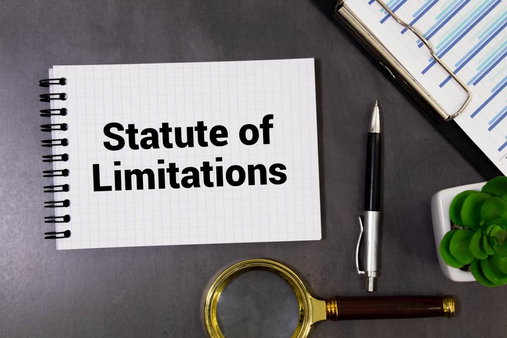 The phrase Statute of limitations is inscribed on a notebook placed against the backdrop of the South African flag, symbolizing the legal framework within the nation.