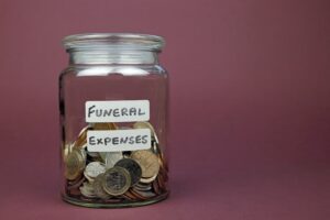 Funeral Expenses Written On A Glass Jar With Money Inside Used To Pay Funeral Costs Concept. 