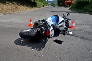 Serious motorcycle accident on a sunny day, close-up of crash. Driving hazards and collision with another vehicle.