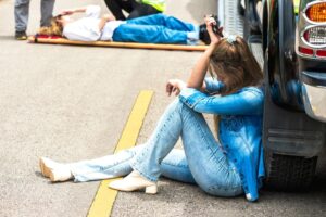 Young woman sitting in distress after a car accident involving a pedestrian on the road.