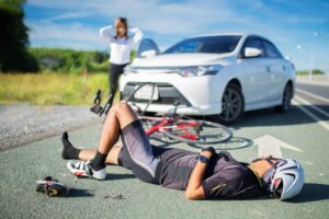 Unconscious male cyclist lying on the road following a traffic accident, with selective focus.