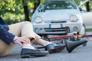 Injured man in pain after a bicycle accident on the asphalt.